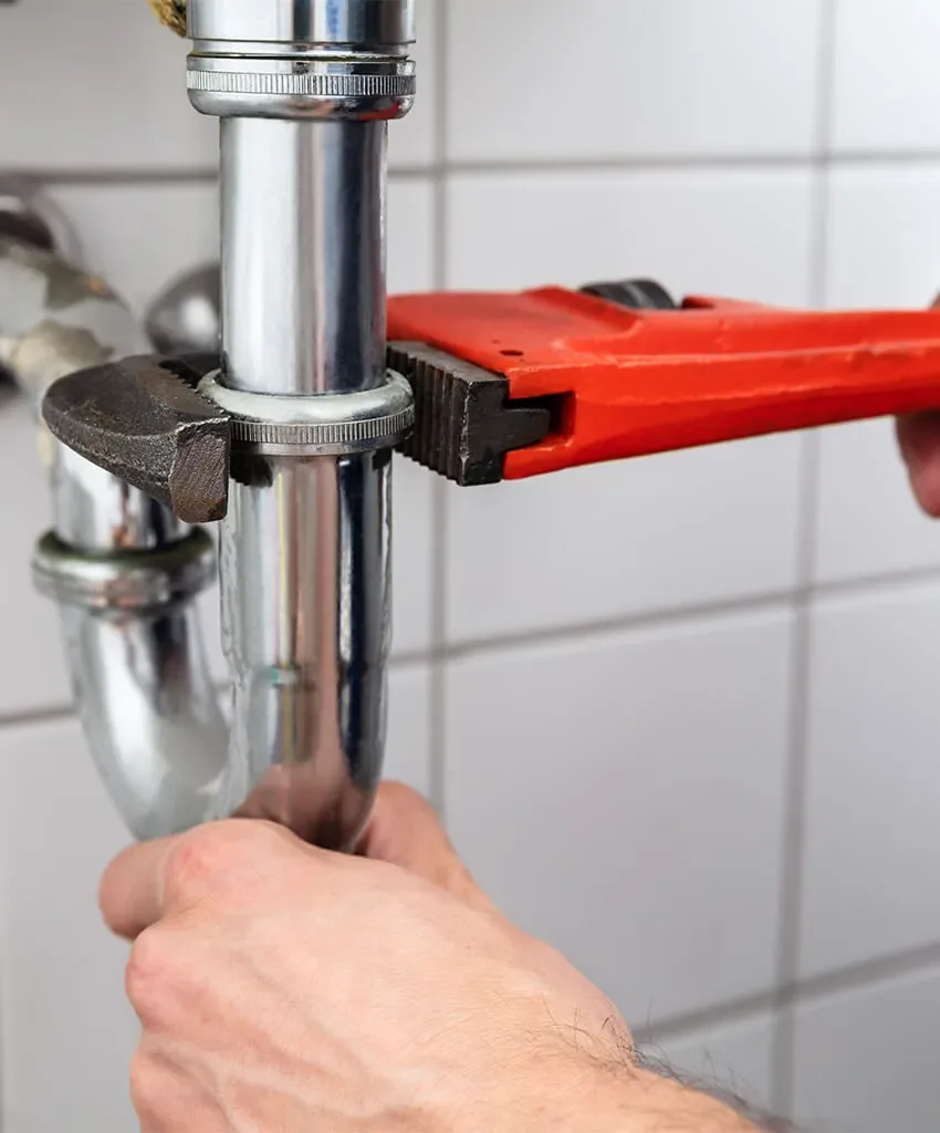 Plumber repairing a pipe beneath a sink